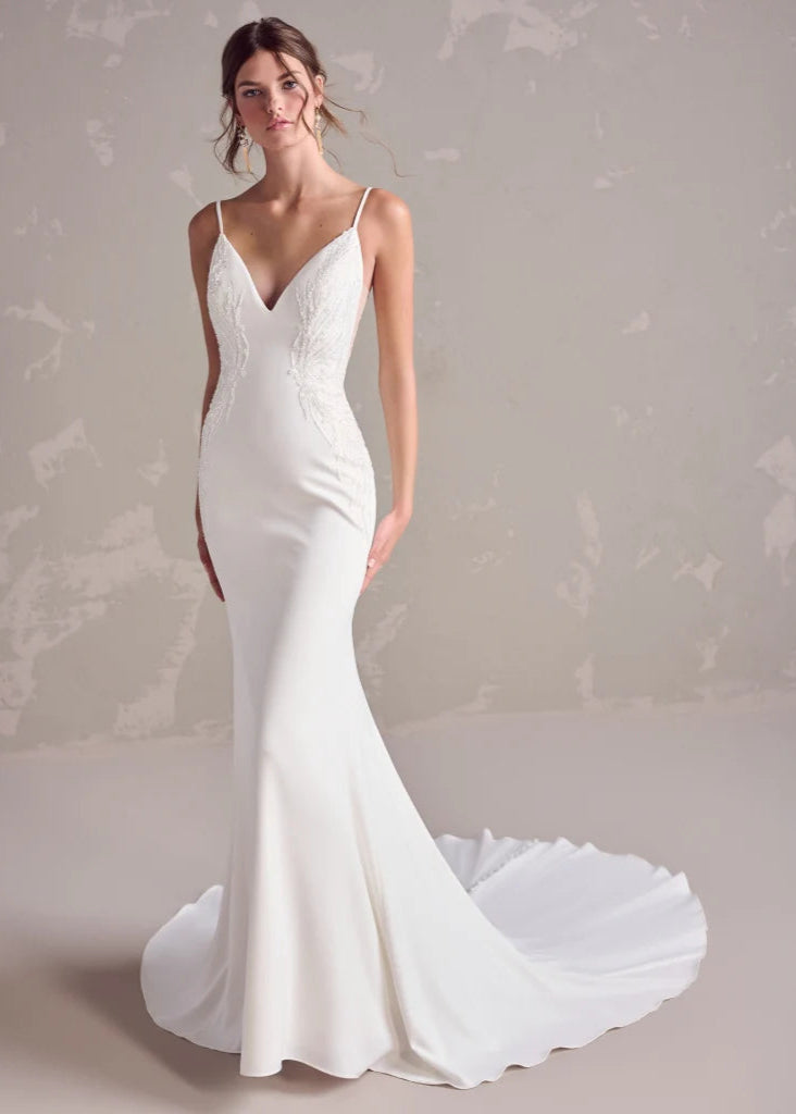 White wedding dress with a long train on a neutral background