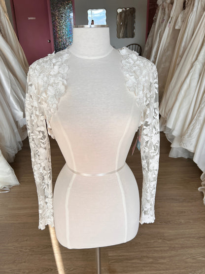 Mannequin wearing a white wedding dress with lace details in a store setting.