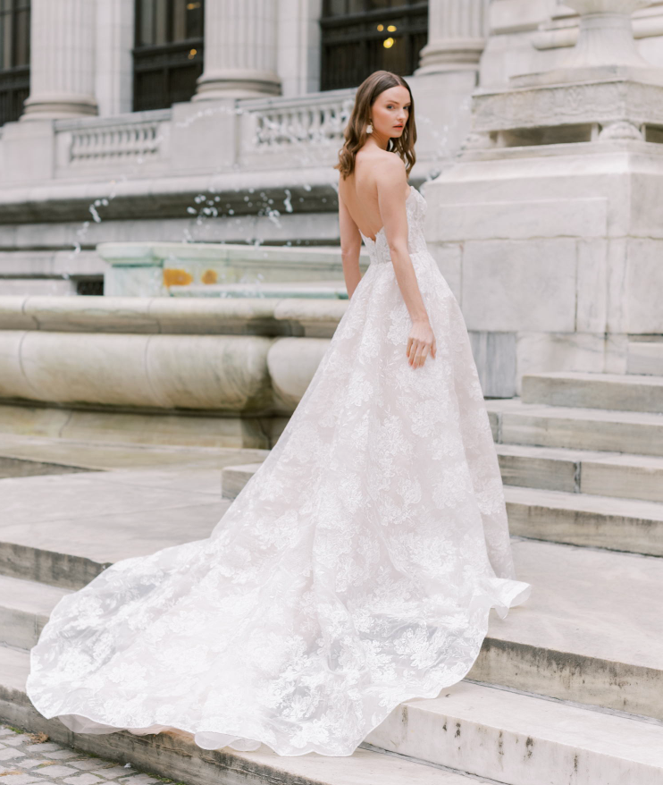 Woman wearing a wedding dress - fully lace ball gown with a soft square neckline side /back view