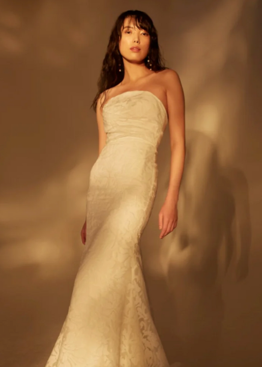 Model wearing Wave by Theia Couture - a strapless floral burnout fit and flare wedding dress - full body front view