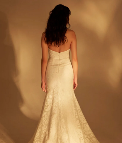 Model wearing Wave by Theia Couture - a strapless floral burnout fit and flare wedding dress, full body back view