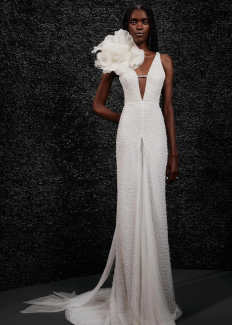 Model wearing Carole by Vera Wang - a fitted beaded wedding dress with a deep V neck and floral shoulder attachment,  full body front view