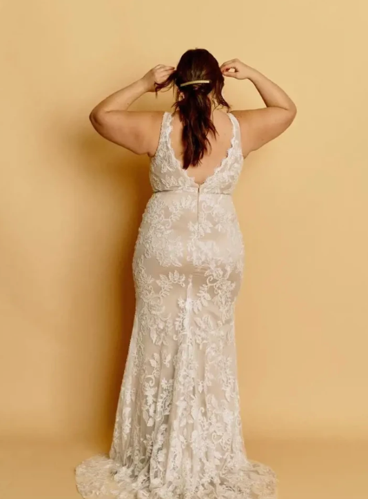 Woman wearing a nude wedding dress, a front slit with a v necklline and full lace