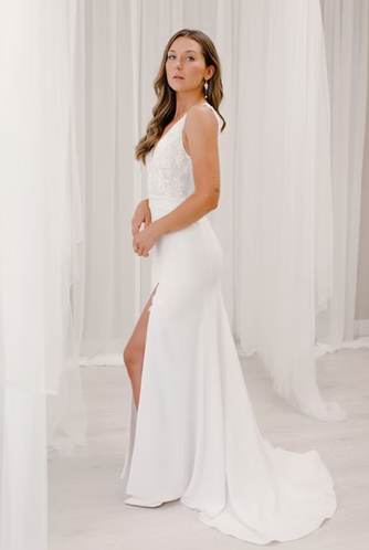 A deep-v neckline with lace appliques flowing down the skirt, complemented by an open leg slit, and a daring low-v back - full body side view