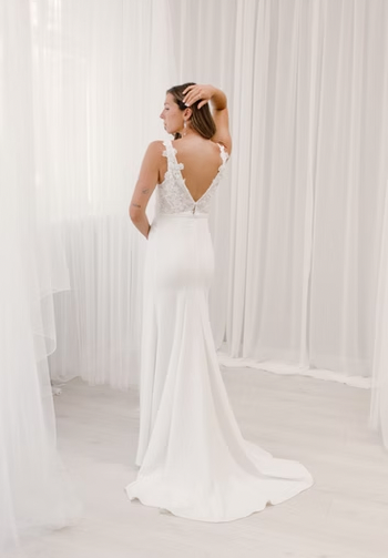 A deep-v neckline with lace appliques flowing down the skirt, complemented by an open leg slit, and a daring low-v back - full body bac view