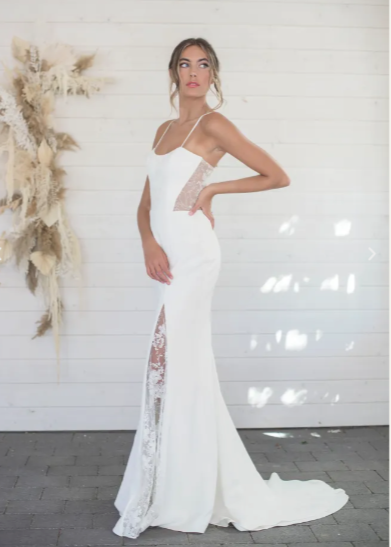  A simple crepe fabric meets its perfect match with a sheer embellished lace back. Aurora by Lillian Wild is a fit-and-flare silhouette with a modified scoop neckline and a very sexy, lace-covered sli