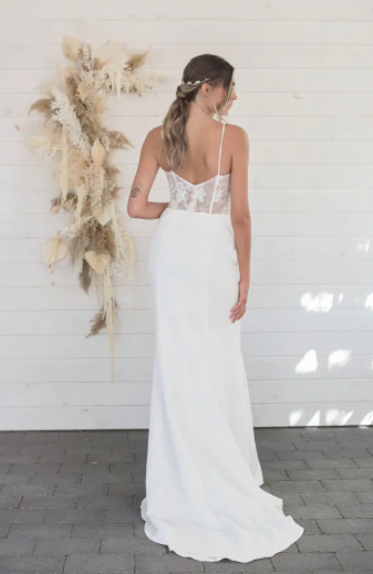  A simple crepe fabric meets its perfect match with a sheer embellished lace back. Aurora by Lillian Wild is a fit-and-flare silhouette with a modified scoop neckline and a very sexy, lace-covered slit - full body back view
