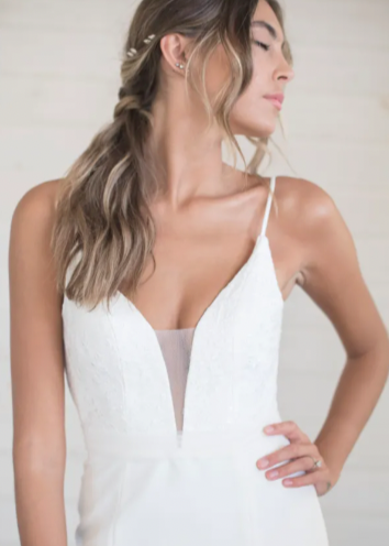 A lace covered plunging sweetheart neckline with illusion tulle creates a super flattering tailored bodice to pair with a sheath silhouette - close up front view