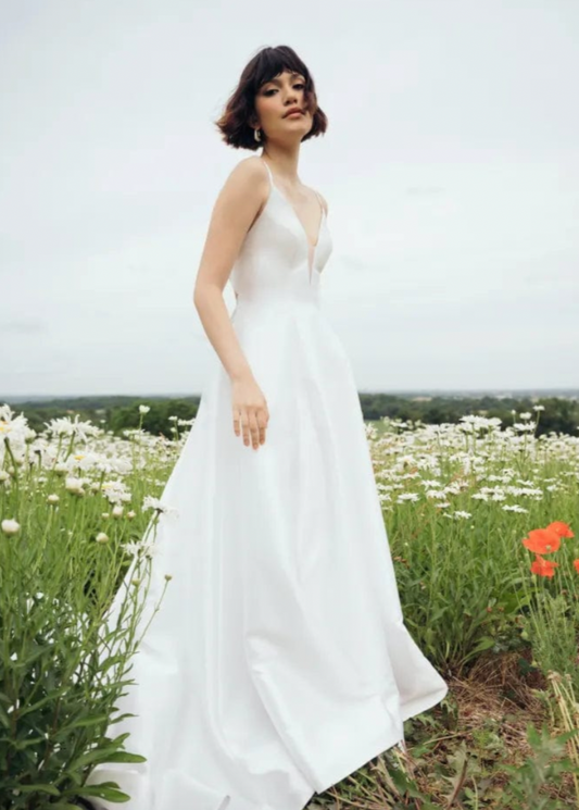 Jenny Yoo Tamson is a classic taffeta A-line wedding dress! This pretty little number features a deep V neckline + pleated skirt.