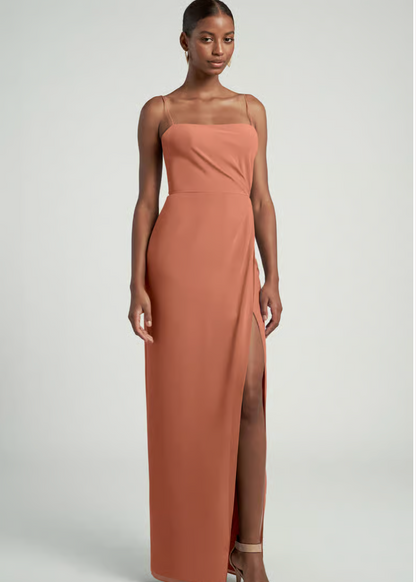 Woman wearing a long, brown dress with a slit on a white background