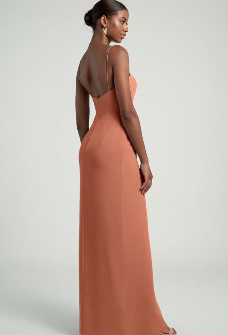 Woman wearing a long, light brown dress against a plain background