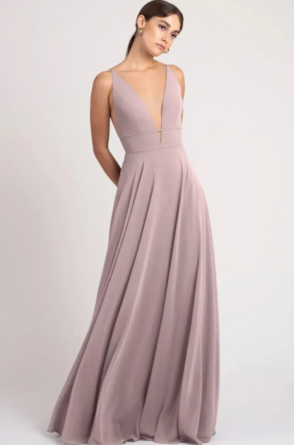 Woman wearing a long, flowing dress with a plunging neckline on a light gray background