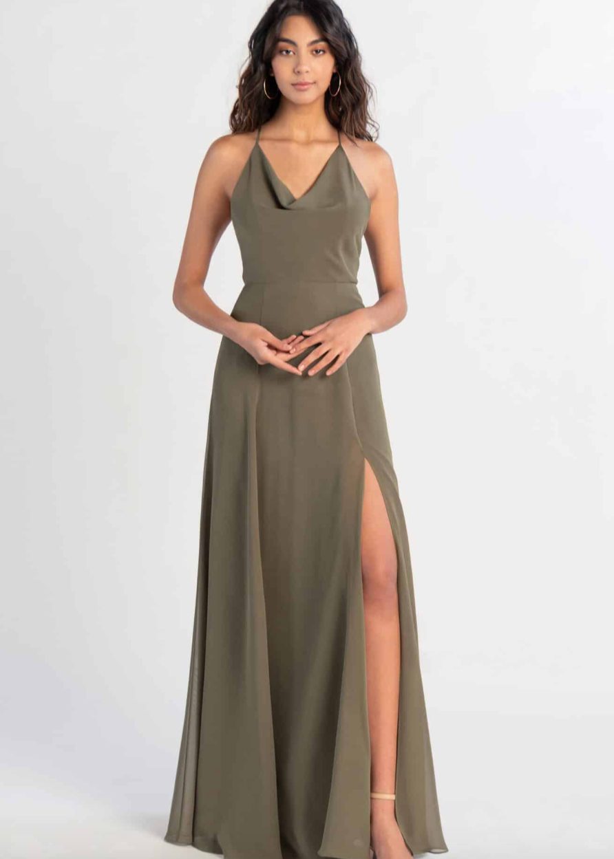 Woman wearing a green halter neck gown with a slit on a white background