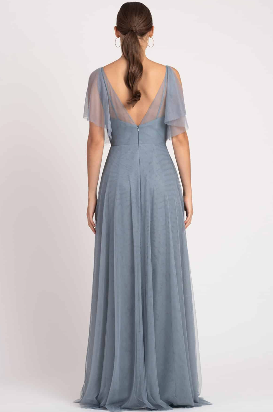 Woman wearing a long, light blue dress with sheer sleeves on a white background