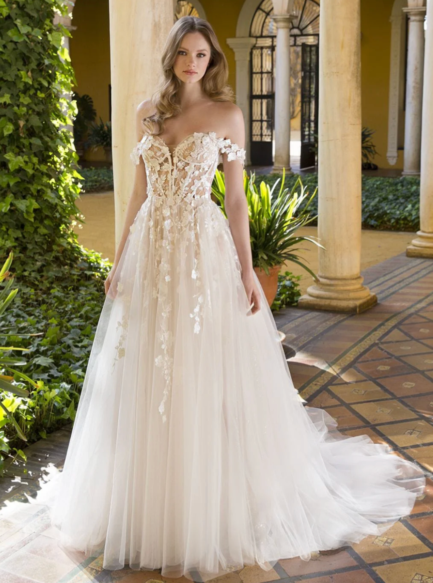 Woman in a white wedding dress standing in an outdoor setting with columns and plants.