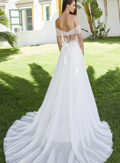 White wedding dress with floral details on a grassy lawn