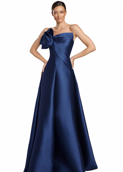 Woman wearing a blue strapless gown with a large bow on a white background