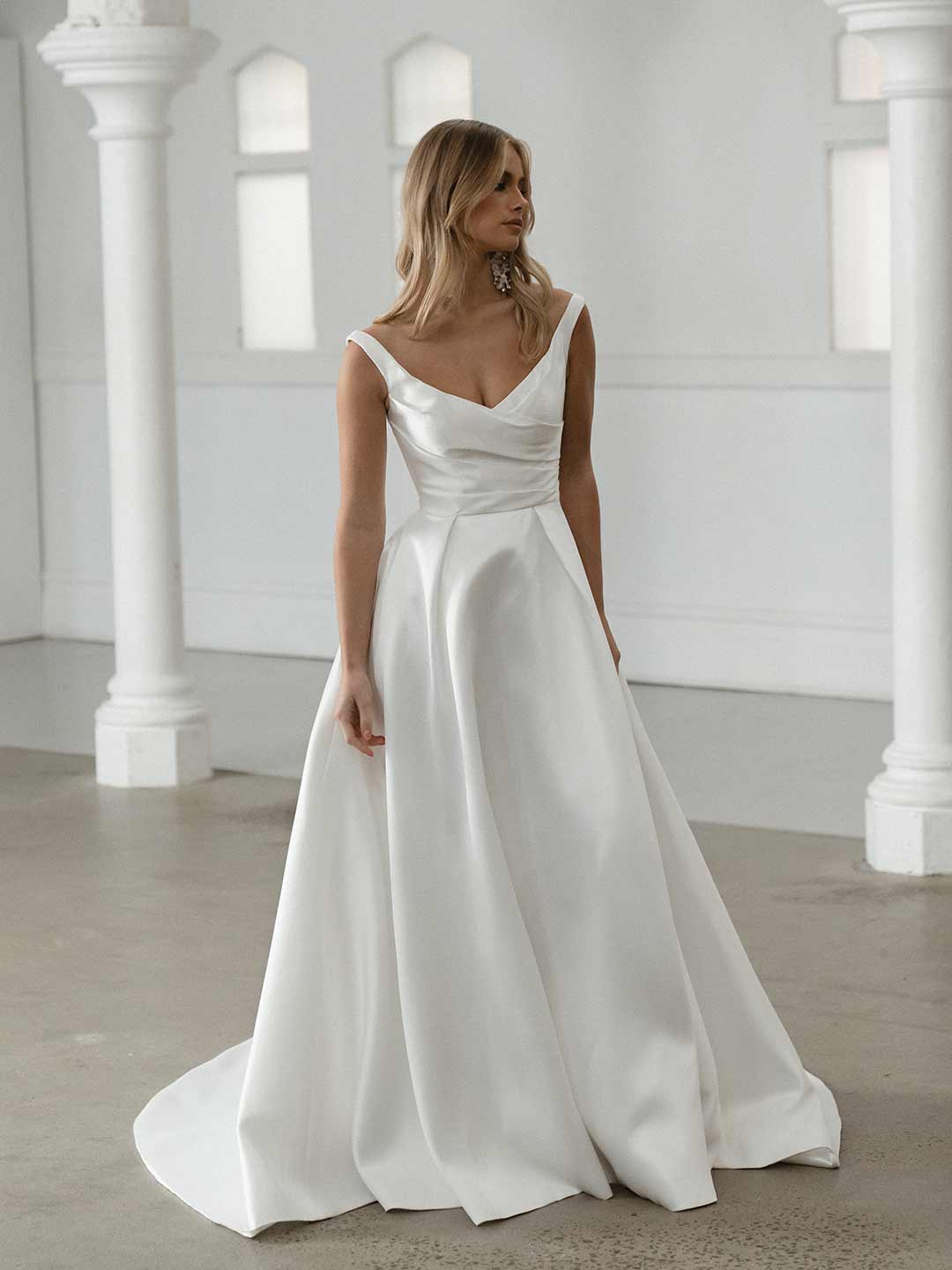 Seldon captures the essence of simple elegance, showcasing a pleated bodice that gracefully complements her shallow V neckline and signature Mikado fabric.