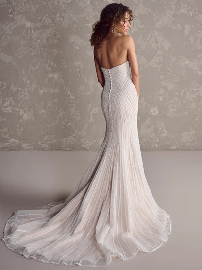Woman wearing a strapless, floor-length white gown with a textured background