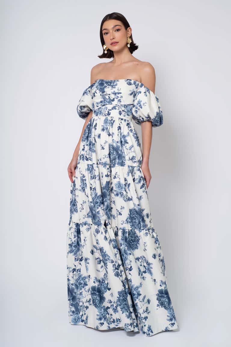 Woman wearing a blue floral off-shoulder gown against a white background