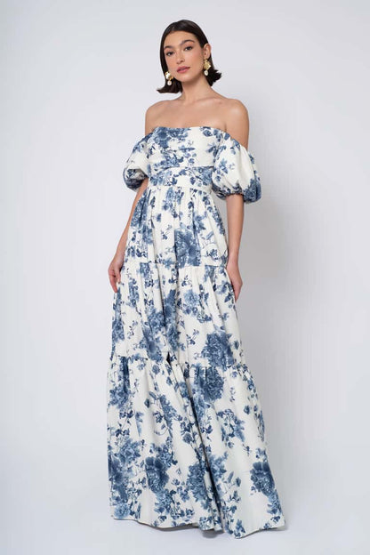 Woman wearing a blue floral off-shoulder gown against a white background