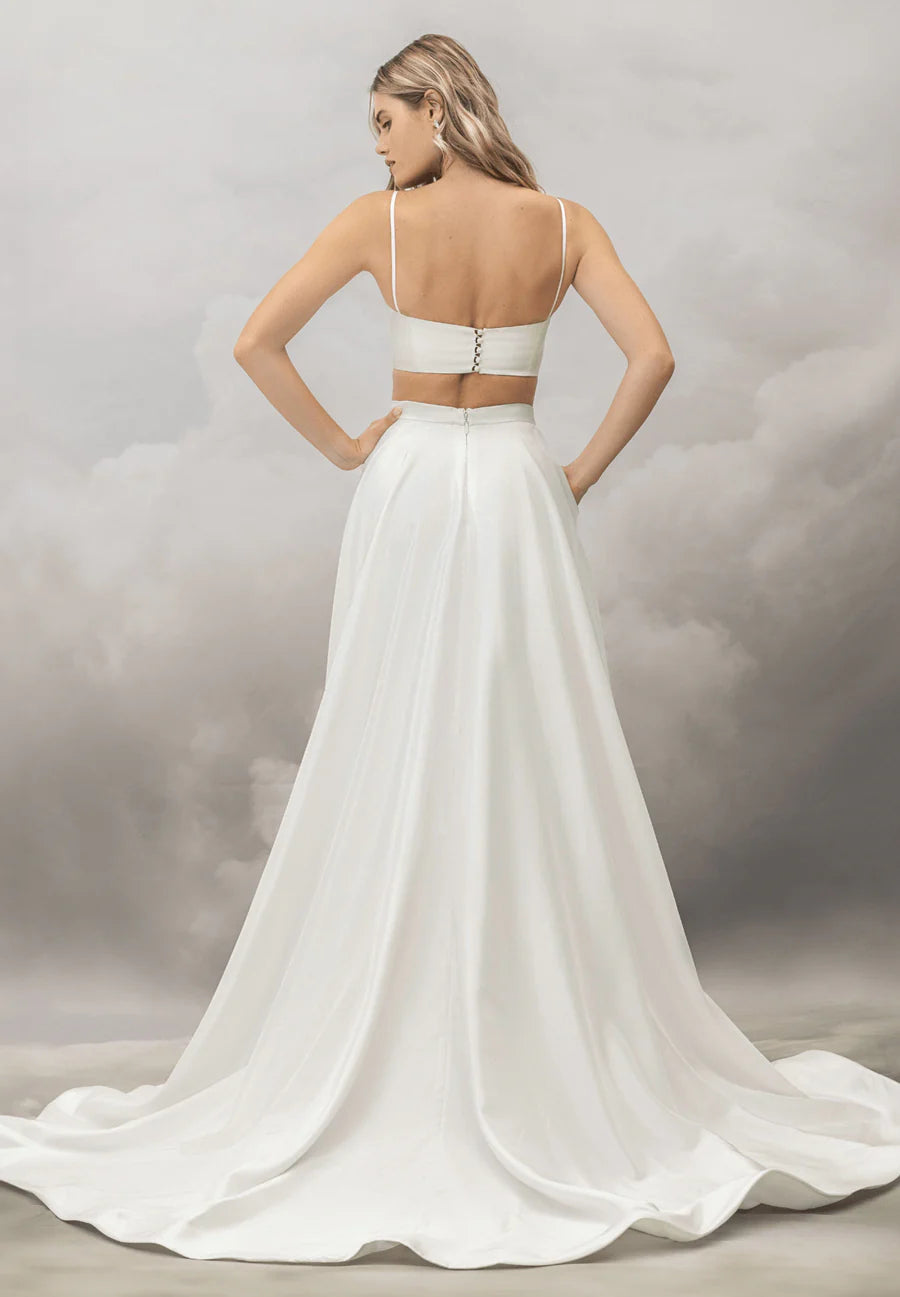 White wedding dress with a flowing train on a neutral background