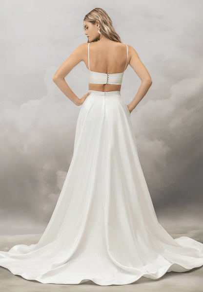 White wedding dress with a flowing train on a neutral background