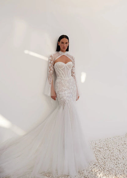 A mermaid silhouette dress in lightskin color made of embroidered lace will help the bride create a seductive image that excites the imagination and causes admiration. A translucent corset with a heart-shaped cutout will emphasize the gorgeous bust. And the lace decor will help to make the waist visually even narrower, covering the structural lines with a decorative strip and draping with a mesh in the form of diagonal small pleats. The top is also delicately decorated with embroidered appliqués.