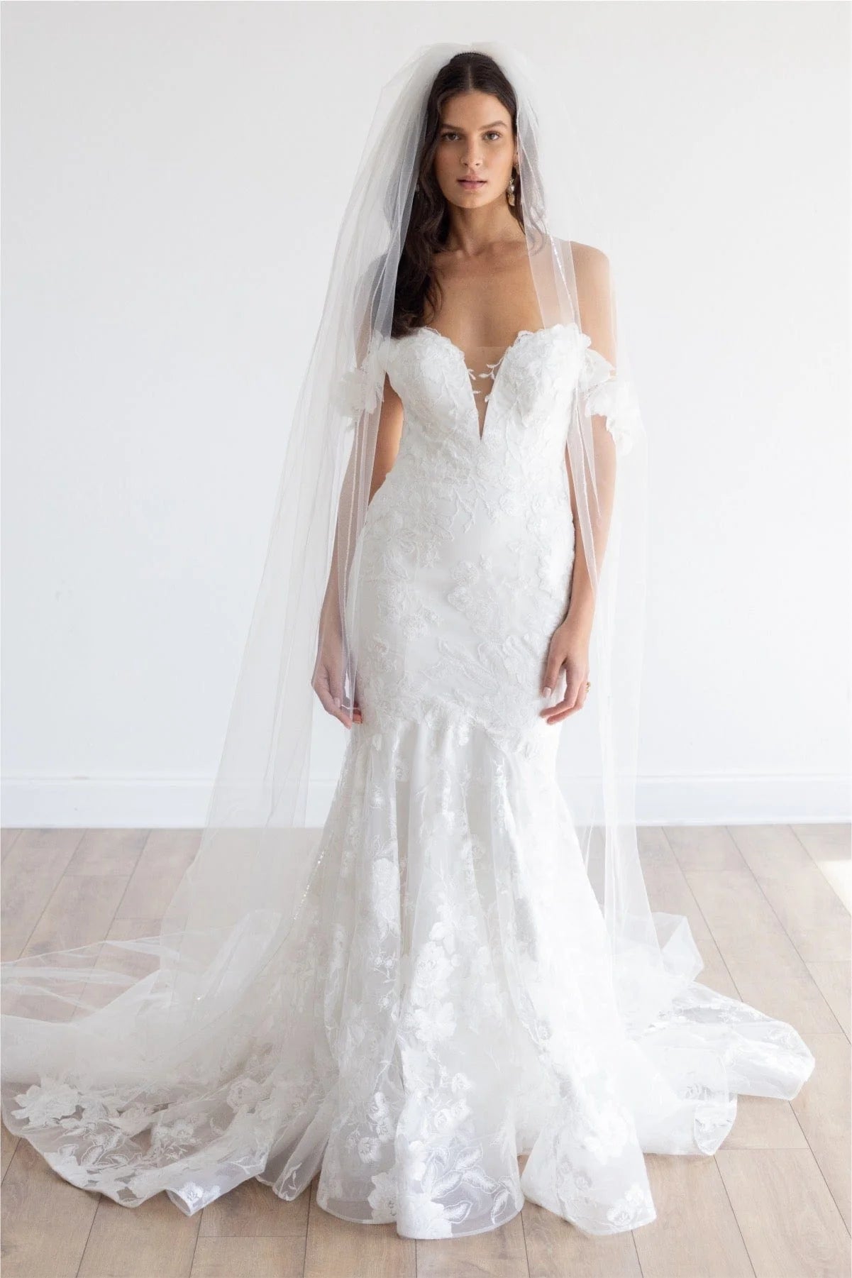This fit and flare silhouette has gorgeous Camellia Floral Lace from head to toe. The Stretch Poly Charmeuse lining allows for comfort while her modern plunge and open illusion back show off your silhouette. Off the shoulder sleeves will give you the sleeve look without adding too much coverage.

