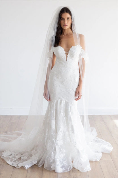 This fit and flare silhouette has gorgeous Camellia Floral Lace from head to toe. The Stretch Poly Charmeuse lining allows for comfort while her modern plunge and open illusion back show off your silhouette. Off the shoulder sleeves will give you the sleeve look without adding too much coverage.

