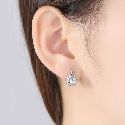 Small silver earrings with a floral shape on a woman's ear