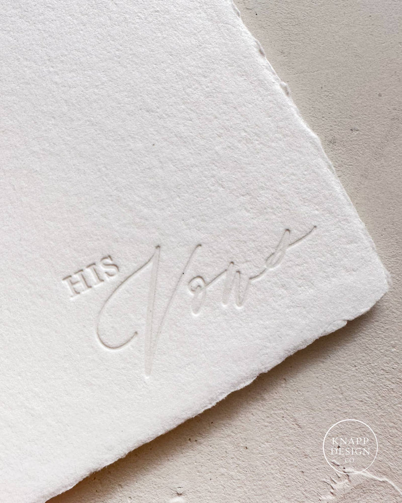 White vow book with white ribbon and "his vows" stamped on bottom right corner