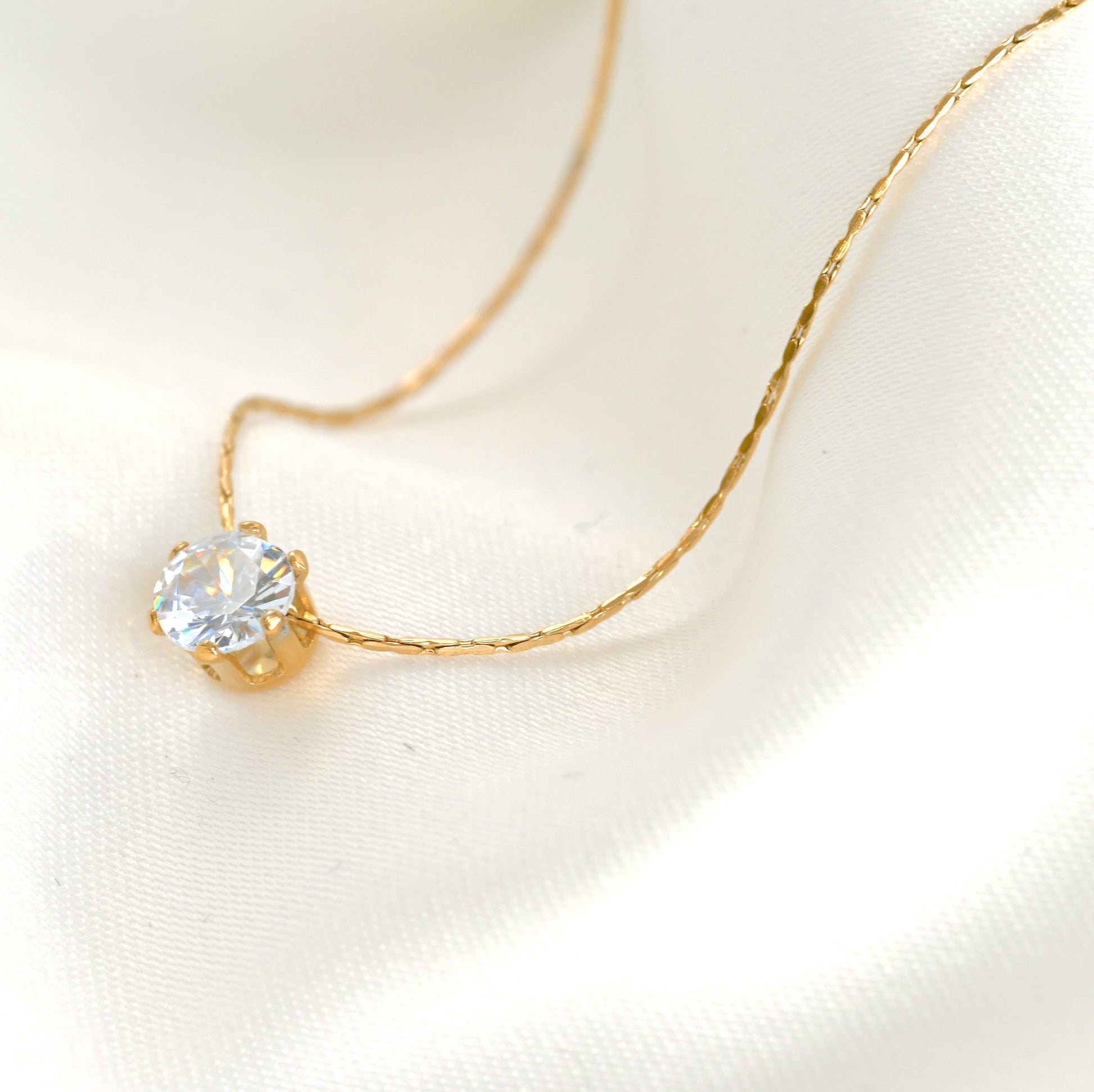 Solitaire necklace with a crystal diamond on a white linen background