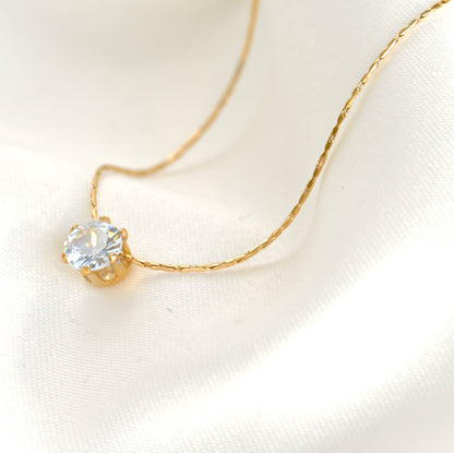 Solitaire necklace with a crystal diamond on a white linen background