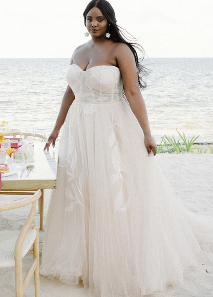 Custom-designed floral motifs dance their way across the structured bodice and trickle down the skirt of this romantic ballgown. Dotted netting sewn into the skirt provides additional dimension, while layers upon layers of tulle melt together to create a soft oatmeal shade to highlight the oversized motifs.