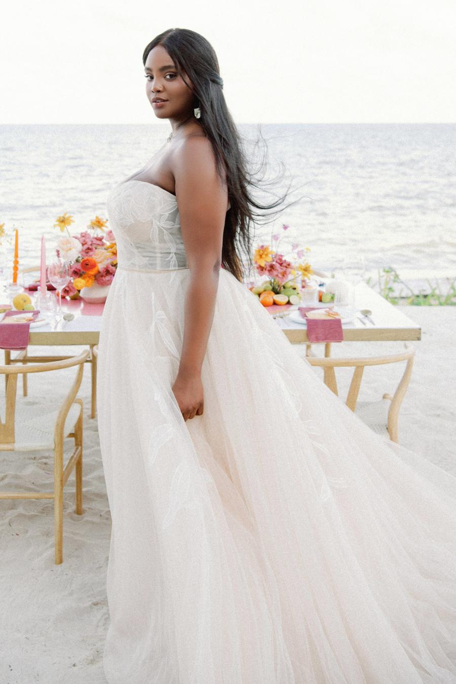 Custom-designed floral motifs dance their way across the structured bodice and trickle down the skirt of this romantic ballgown. Dotted netting sewn into the skirt provides additional dimension, while layers upon layers of tulle melt together to create a soft oatmeal shade to highlight the oversized motifs.