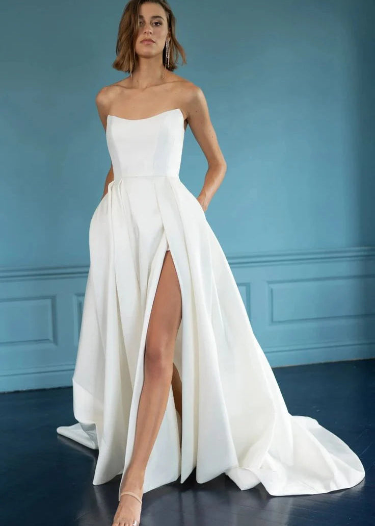 The Mollie gown adds thoughtful details to a classic silhouette. Featuring a beautifully structured bodice with a sultry scoop neckline with high peaks, the full A line skirt is elevated by inverted box pleats and a dramatic side slit. The sheer illusion back with exposed boning ensures a beautiful view from any angle, and covered buttons to the hem add one last classic bridal detail.
