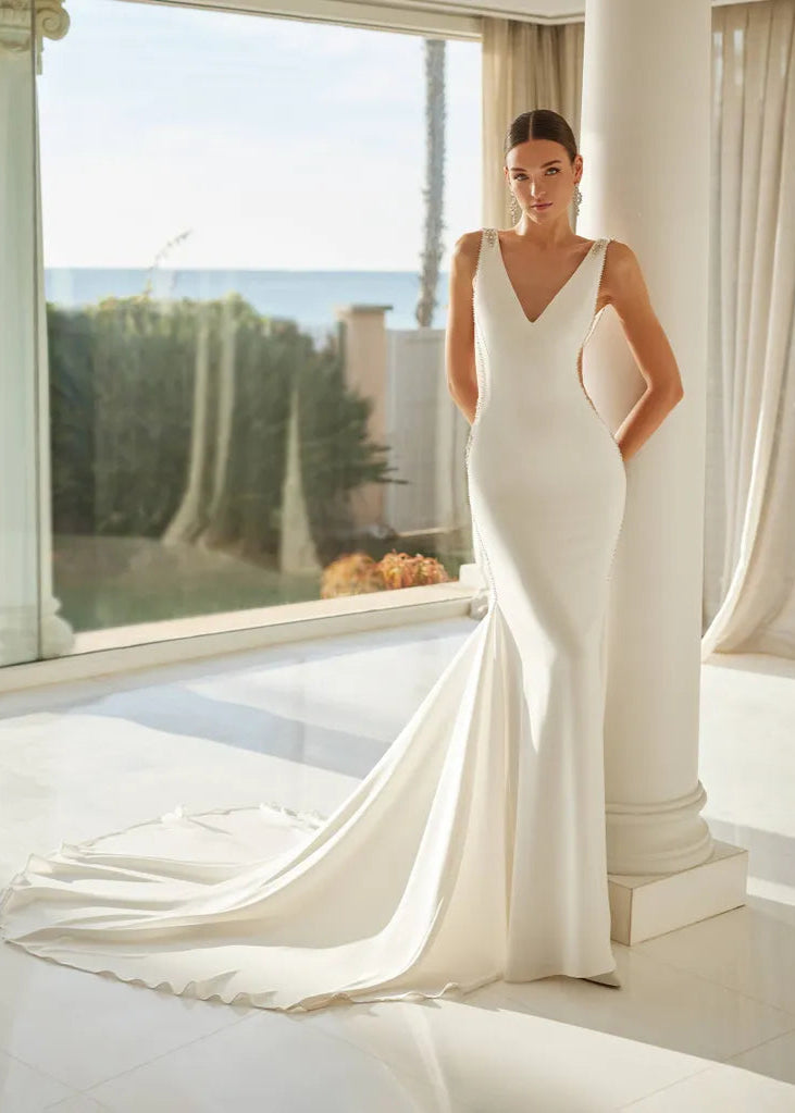 Young woman wearing a fitted wedding dress with a deep v and beaded details - FRONT VIEW
