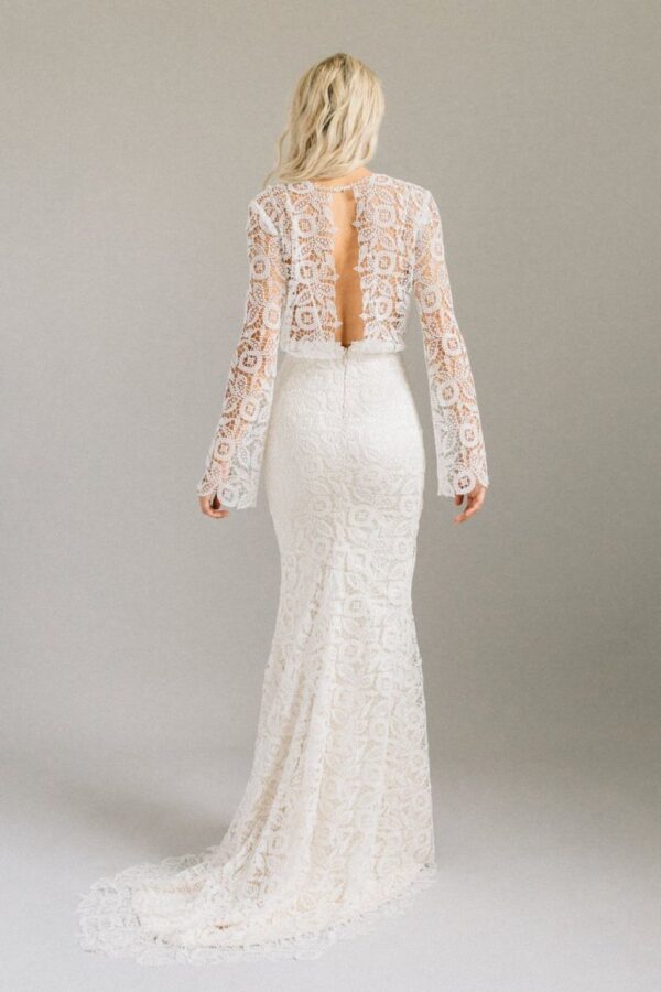 Shes a bell sleeved lace gown with a centre slit and a keyhole back