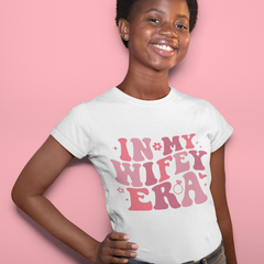 Young woman wearing a white shirt that says “in my wifey era”