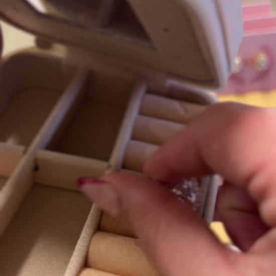 Putting earrings into a cream and bow colored jewelry box