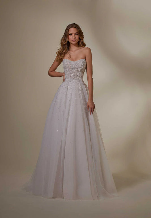 Woman wearing a strapless, beaded wedding dress against a neutral background