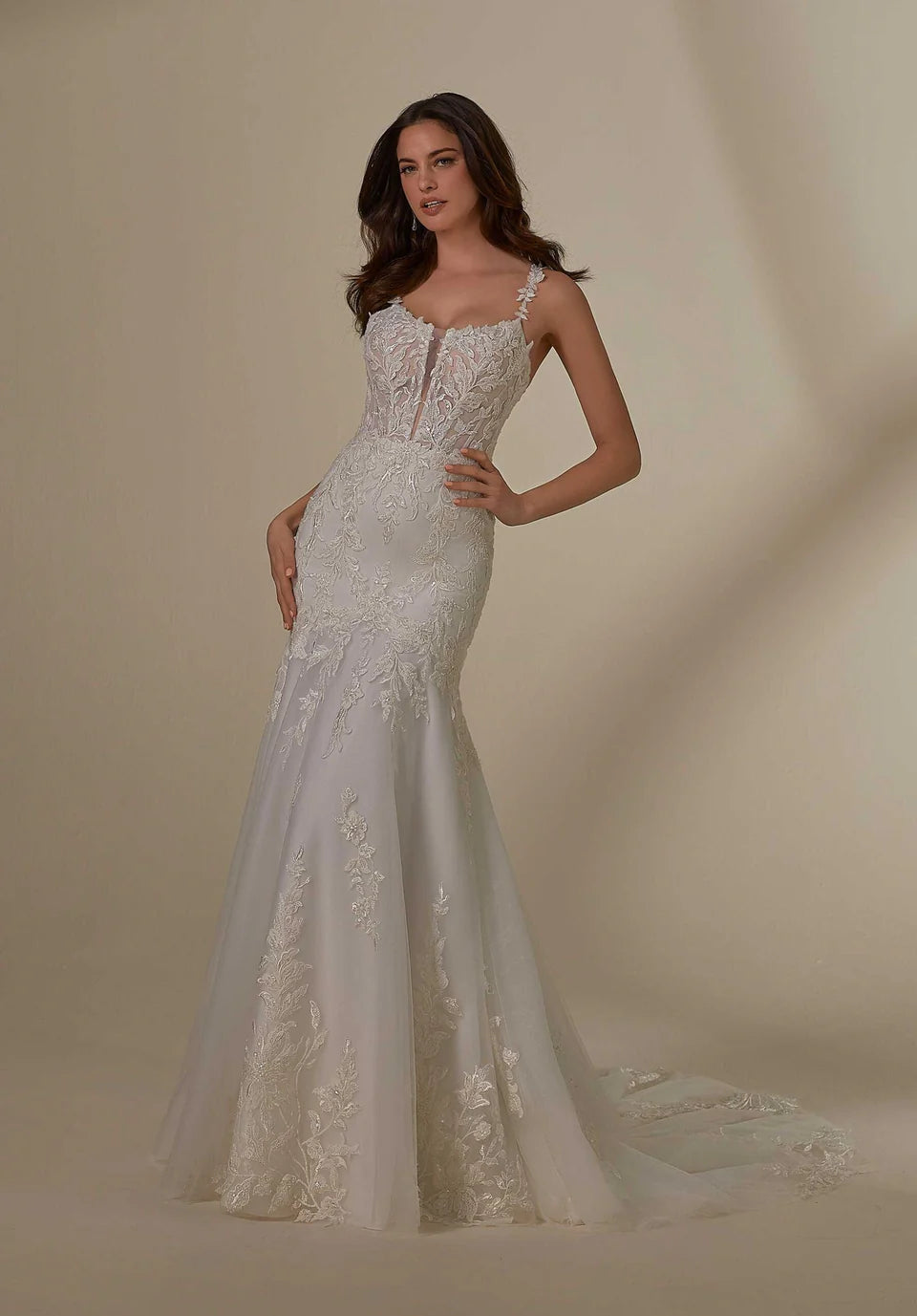 Woman wearing a white lace wedding dress against a beige background