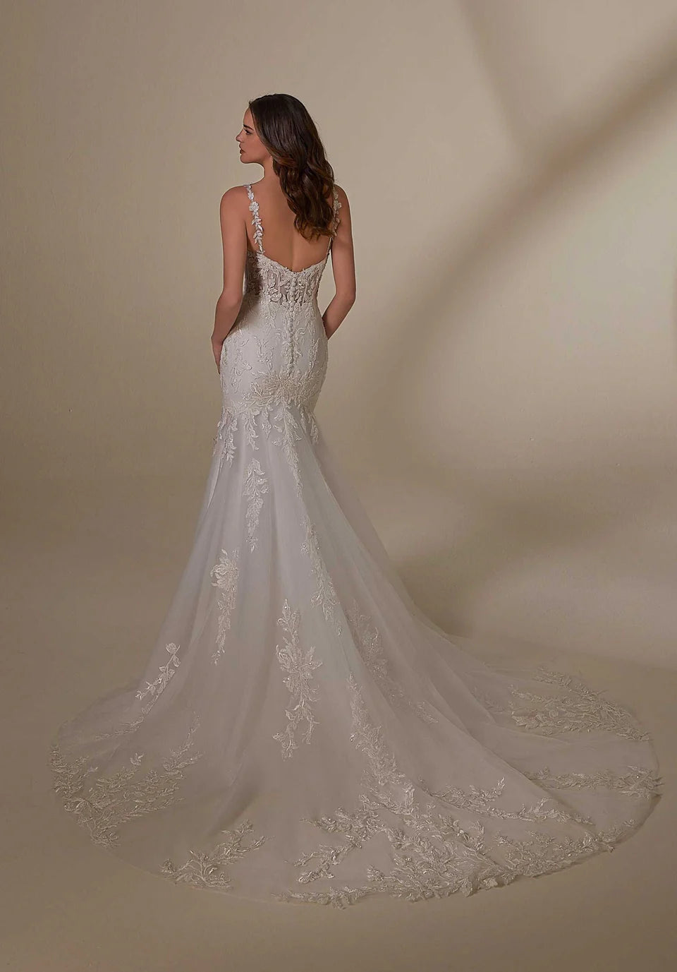 Woman wearing a white lace wedding dress against a beige background