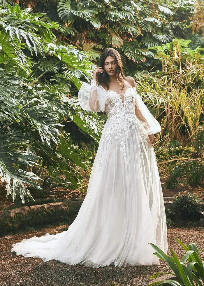 Young woman wearing a flowy a-line wedding dress with lace, florals and puffy sleeves - front view