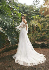 Young woman wearing a flowy a-line wedding dress with lace, florals and puffy sleeves - - back view