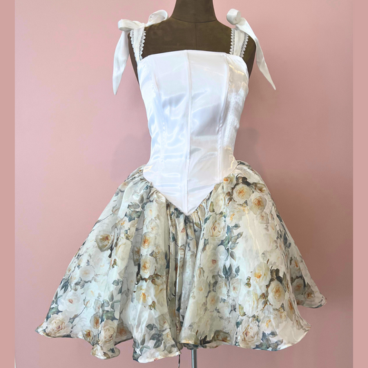 Mannequin wearing a white top and floral skirt against a pink background
