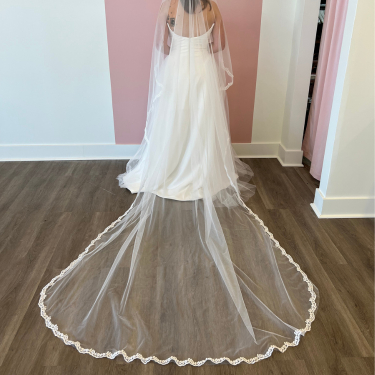 White wedding dress with a long train on a wooden floor.