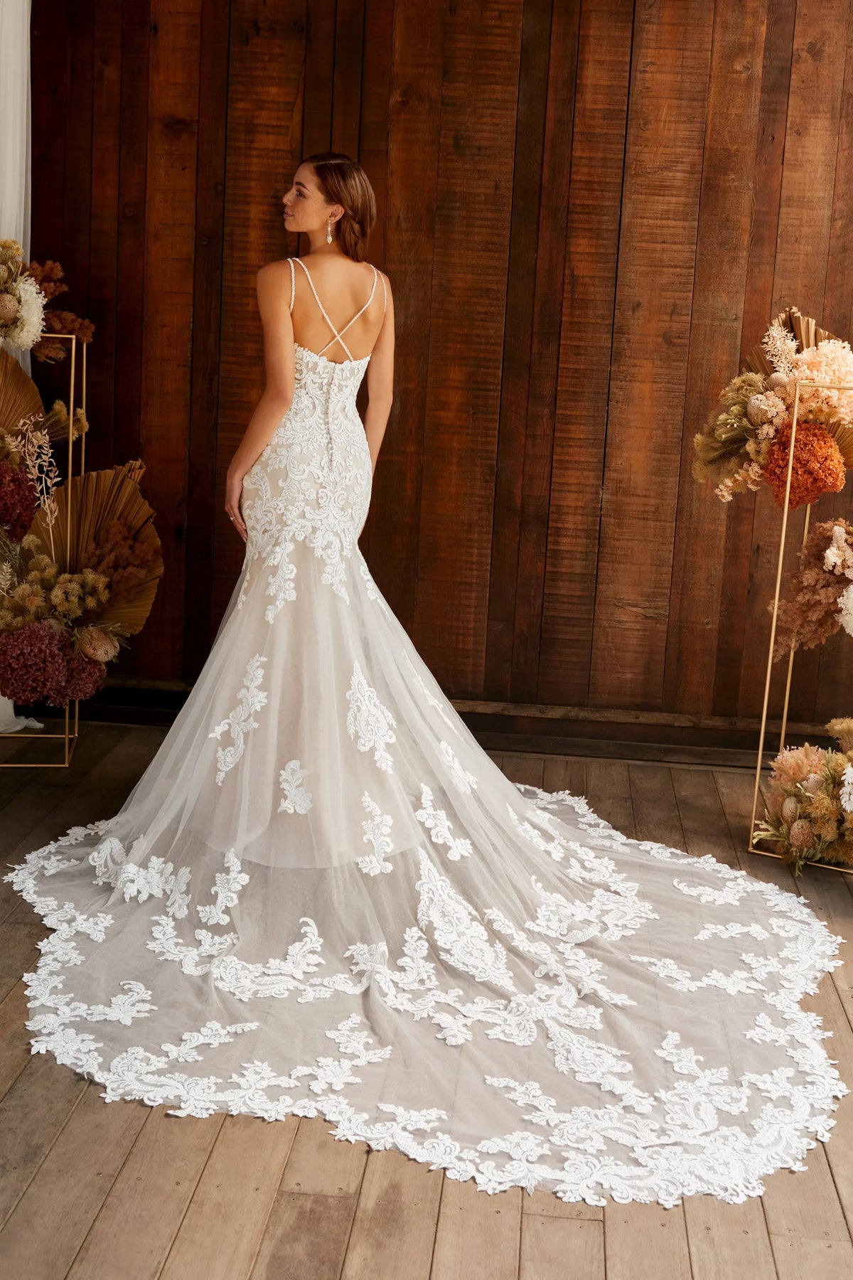 Model showing off the back of Kaylee by Sophia Tolli fit and flare v-neck wedding dress with lace and beading at NKIN bridal outlet in Ottawa. The back is a cross cross with fabric covered buttons and a petal long train