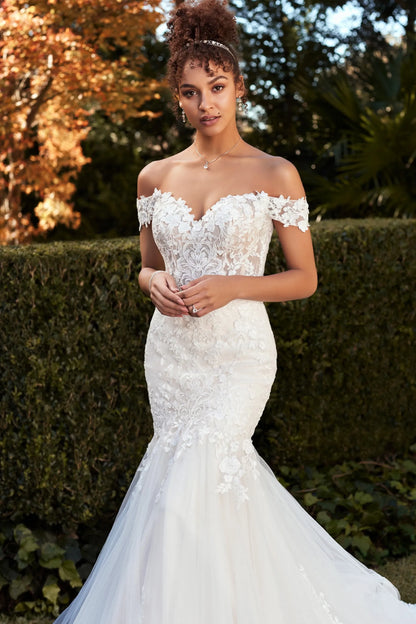 A woman wearing an off-the-shoulder white lace mermaid wedding gown, Molly by Sophia Tolli, available in size 14 at NKIN Bridal Outlet Ottawa